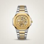 Two-tone stainless steel skeleton watch with gold bezel, silver bracelet, and exposed automatic movement.