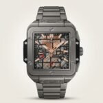 Square grey titanium-style skeleton watch with rose gold hands, visible movement, and rubber-inlaid metal bracelet.