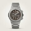 Silver-tone chronograph watch with brown skeleton dial, three sub-dials, tachymeter bezel, and stainless steel bracelet.