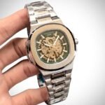 Two-tone stainless steel skeleton watch with gold bezel, silver bracelet, and exposed automatic movement.