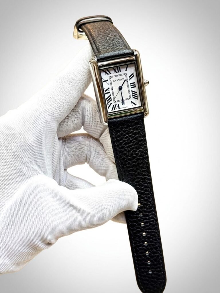 Silver rectangular tank-style watch with white dial, black Roman numerals, and brown leather strap.