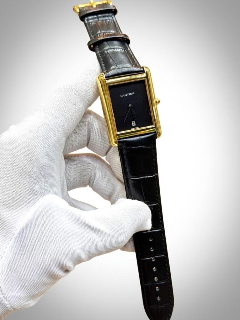 Silver rectangular tank-style watch with white dial, black Roman numerals, and brown leather strap.
