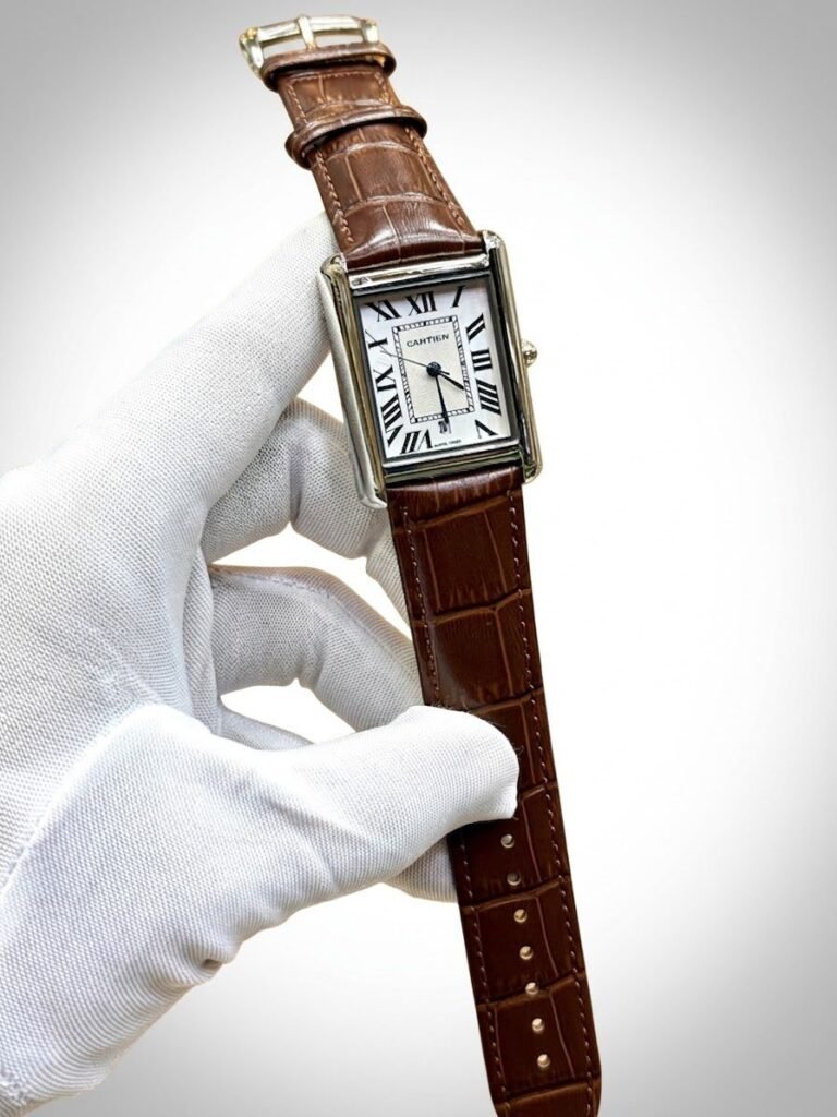 Silver rectangular tank-style watch with white dial, black Roman numerals, and brown leather strap.