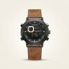 Tubular dual-time digital watch with all-black case, green button accent, and brown leather strap.
