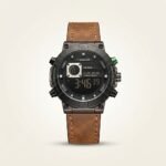 Tubular dual-time digital watch with all-black case, green button accent, and brown leather strap.