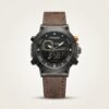 Tubular dual-time digital watch with black case, gold accents, and brown leather strap.