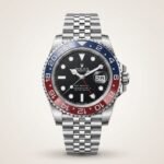 Silver-tone GMT style watch with black dial, red and blue rotating bezel, and jubilee bracelet held in hand.