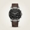 Tubular chronograph watch with black dial, silver-tone case, and brown leather strap.