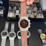 Silver-tone quartz watch with brown dial, Arabic numerals, date window, and brown leather strap.