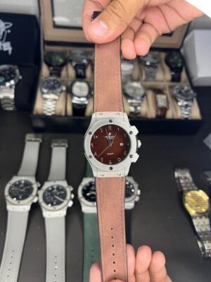 Silver-tone quartz watch with brown dial, Arabic numerals, date window, and brown leather strap.