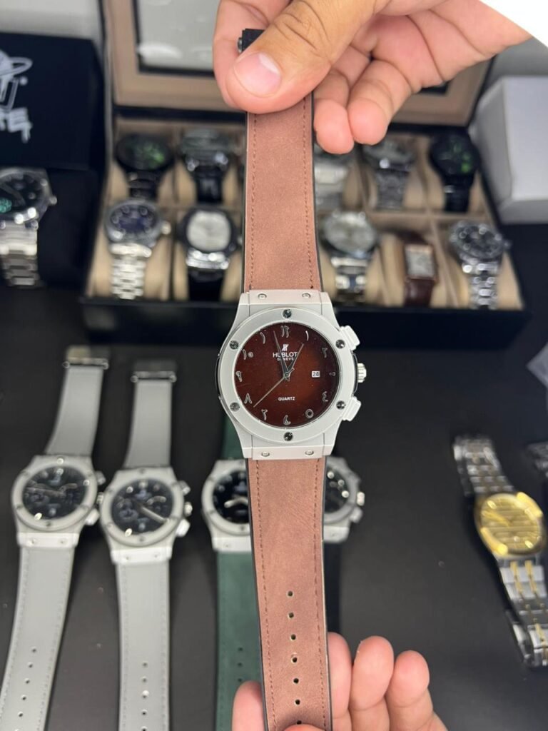 Silver-tone quartz watch with brown dial, Arabic numerals, date window, and brown leather strap.