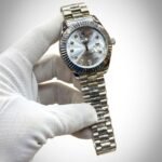 Silver-tone stainless steel watch with fluted bezel, sunburst dial, diamond hour markers, and date window at 3 o'clock.
