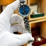 CURREN 9106 women's silver-tone watch with blue sunburst dial and crystal markers.