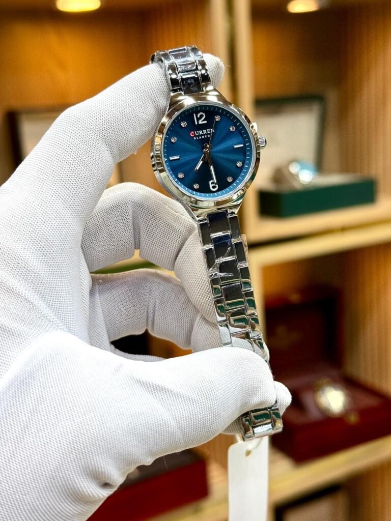 CURREN 9106 women's silver-tone watch with blue sunburst dial and crystal markers.