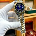 Two-tone silver and gold luxury style watch with blue sunburst dial, crystal markers, gold fluted bezel, and jubilee bracelet.