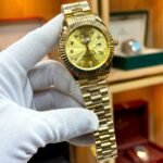 Full gold luxury style watch with champagne sunburst dial, crystal markers, fluted bezel, day window, and gold presidential bracelet.