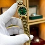 CURREN 9100 women's gold-tone watch with green sunburst dial, crystal markers, and rhinestone bezel.