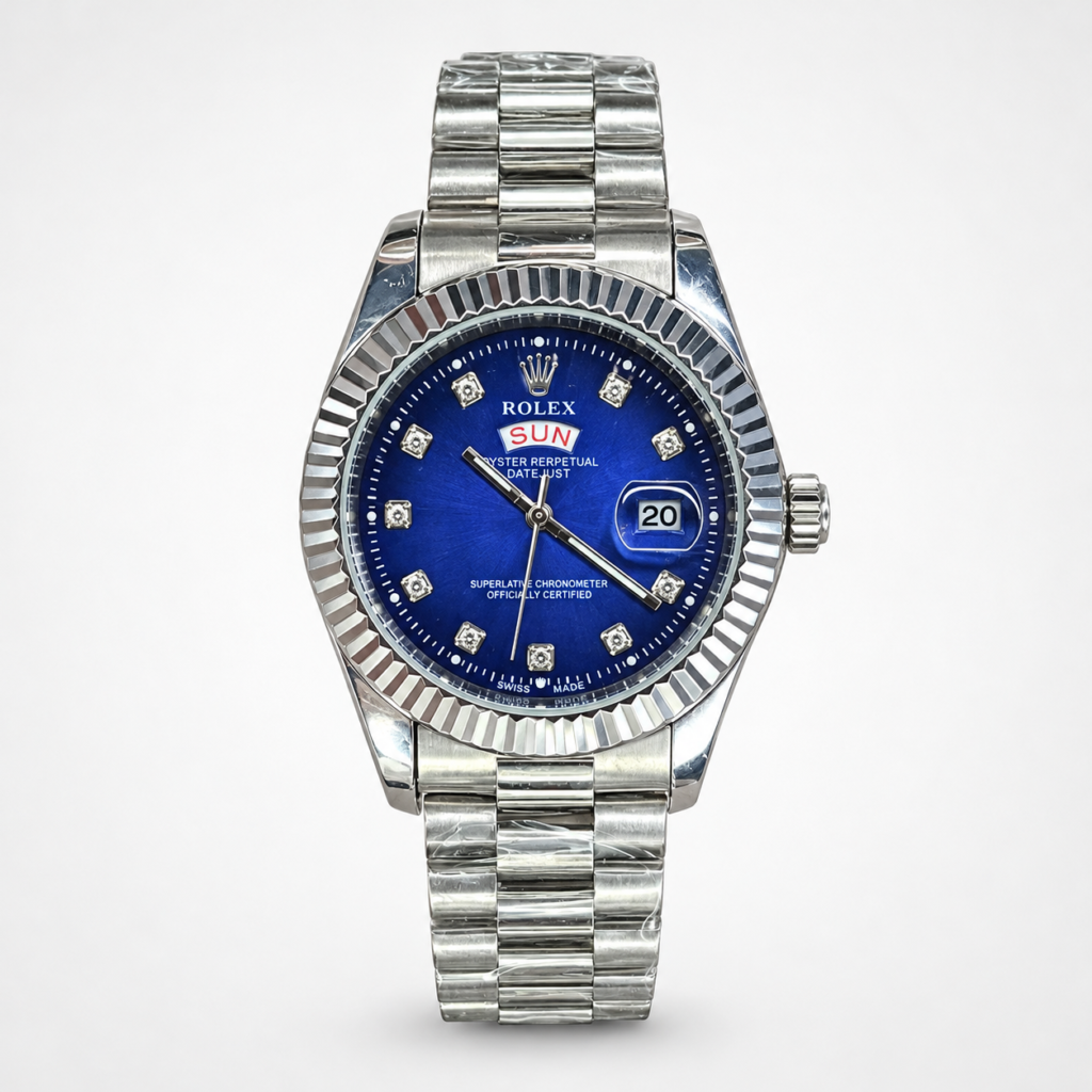 Silver men's luxury watch with blue dial, crystal hour markers, fluted bezel, day-date window, and silver jubilee bracelet.