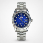 Silver men's luxury watch with blue dial, crystal hour markers, fluted bezel, day-date window, and silver jubilee bracelet.