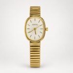 Gold oval ladies watch with white textured dial, gold indices, and expanding link bracelet.